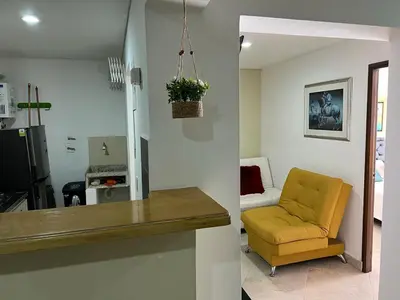 a living room with a yellow chair and a kitchen at Apartamento Amoblado laureles estadio in Medellín