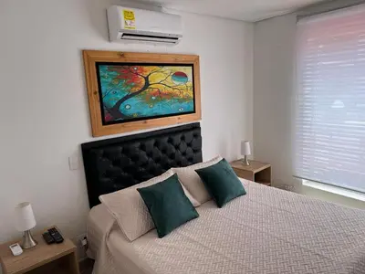 a bedroom with a bed with a painting on the wall at Apartamento Amoblado laureles estadio in Medellín