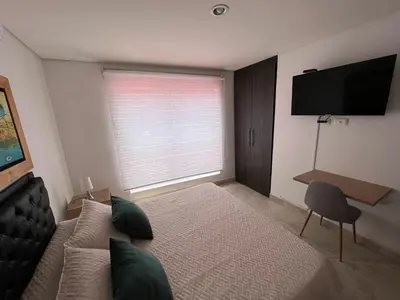 a bedroom with a bed and a flat screen tv at Apartamento Amoblado laureles estadio in Medellín