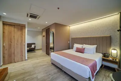 a bedroom with a large bed and a living room at Eutopiq Hotel in Medellín