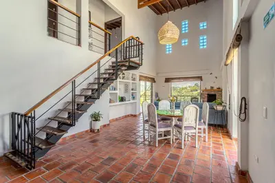 a dining room with a staircase and a table and chairs at La Villa, Espectaculares vistas al lago Peñol-Guatape in Guatapé