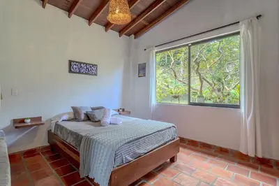 a bedroom with a bed and a large window at La Villa, Espectaculares vistas al lago Peñol-Guatape in Guatapé