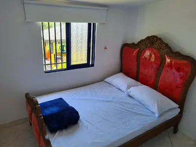 a bedroom with a bed with a red headboard and a window at Finca Hotel Alto la María in Angelópolis