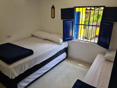 two beds in a room with a window at Finca Hotel Alto la María in Angelópolis