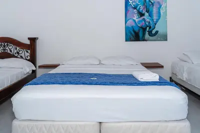 a white bed in a room with a painting on the wall at Casa Hotel Victoria Real in Mariquita