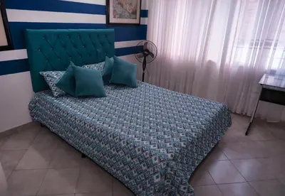 a bedroom with a bed with a green headboard at Casa La Palma Habitación Cielo in Medellín