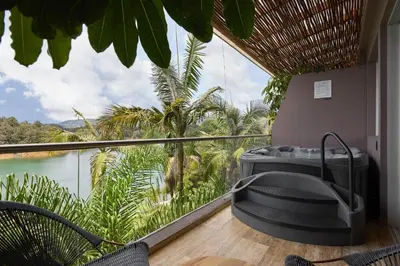 a balcony with a bath tub and a view of the jungle at Tau House in Guatapé