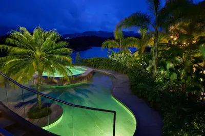 a resort swimming pool with palm trees and water at Tau House in Guatapé