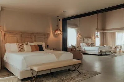 a bedroom with a large white bed and a living room at Tau House in Guatapé