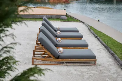 a row of lounges on the sand next to the water at Tau House in Guatapé