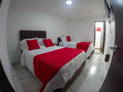 two beds in a room with red and white sheets at El Edén hotel Campestre in Pensilvania