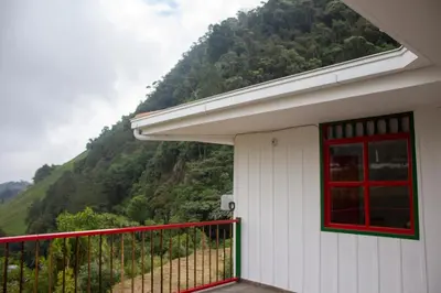 a white house with a red window and a mountain at El Edén hotel Campestre in Pensilvania