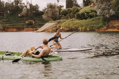 two people are on a paddle board in the water at KABINE in El Peñol
