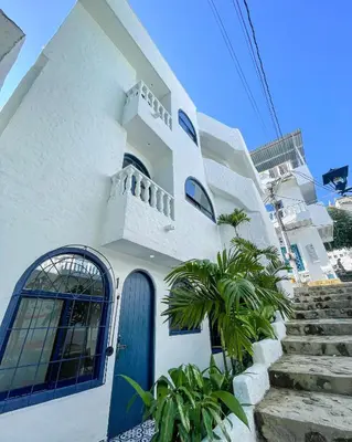 a white house with a blue door and stairs at El santorini colombiano en Doradal in Puerto Triunfo