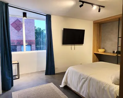 a bedroom with a bed and a tv and a window at Center City Flats - Apartments in El Poblado near Park Lleras, Medellin! in Medellín