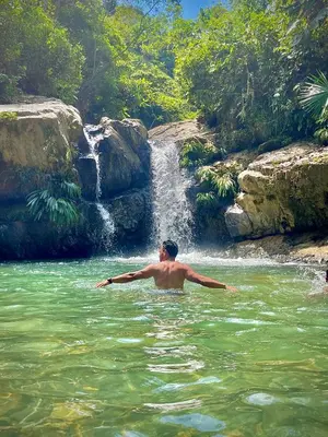 a man in the water in front of a waterfall at Cabañas Camino al Agua - Cocorná in Cocorná