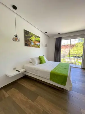 a bedroom with a large white bed with green sheets at Hotel Monte Bello in Doradal