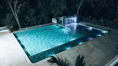an infinity pool with a waterfall at night at Hotel Monte Bello in Doradal