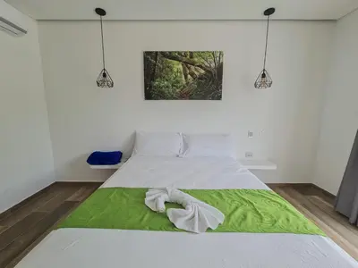 a bedroom with a bed with a green and white blanket at Hotel Monte Bello in Doradal