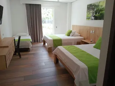 a hotel room with two beds with green sheets at Hotel Monte Bello in Doradal