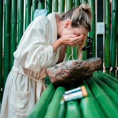 a woman in a robe drinking from a fountain at Chamí Glamping in Manizales