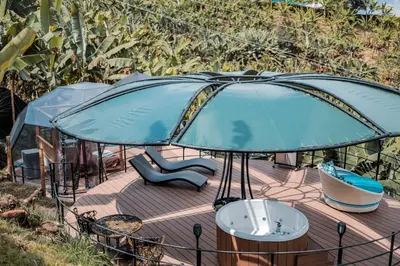 a circular deck with a blue umbrella and a bench at Chamí Glamping in Manizales