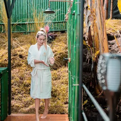 a woman in a dress standing next to a green building at Chamí Glamping in Manizales