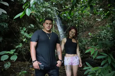 a man and a woman standing in front of a waterfall at Chamí Glamping in Manizales