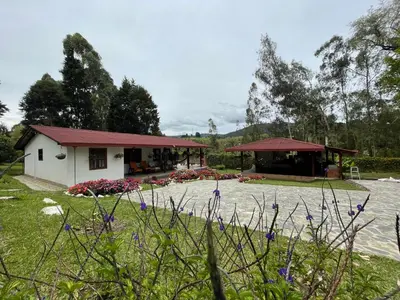 a white building with a red roof in a yard at finca Encanto in Guarne