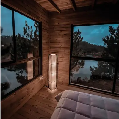 a room with two large windows and a bed at Cabañas Refugio Himalaya in Guatapé