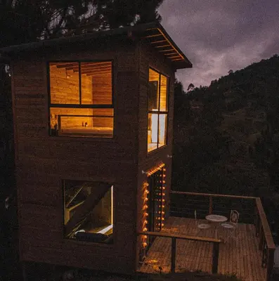 a small house with windows on a deck at night at Cabañas Refugio Himalaya in Guatapé