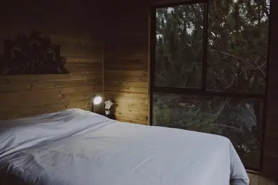 a bedroom with a bed and a large window at Cabañas Refugio Himalaya in Guatapé