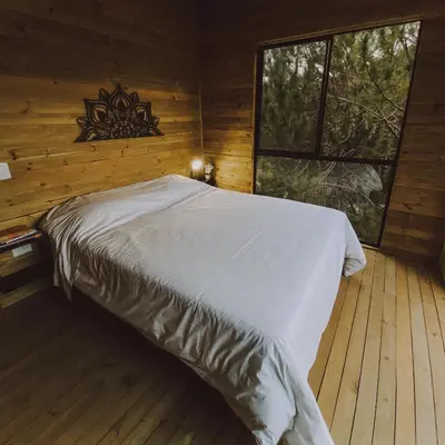 a bedroom with a bed in a log cabin at Cabañas Refugio Himalaya in Guatapé