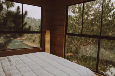 a bedroom with a large bed and large windows at Cabañas Refugio Himalaya in Guatapé
