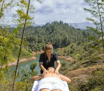 a woman doing a massage on a mans back in front of a river at Cabañas Refugio Himalaya in Guatapé
