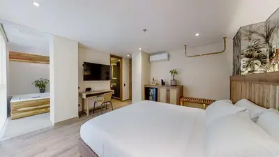a bedroom with a large white bed and a bathroom at Origen Hotel Boutique in Medellín