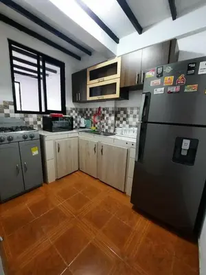 a kitchen with a black refrigerator and a wooden floor at APARTAMENTO CON VISTA A LAS MONTAÑAS CAPACIDAD 6 PERSONAS SECTOR VILLAMARIA in Villamaría