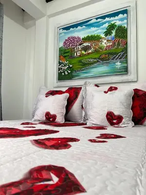 a bed with red flowers on it with a painting at APARTAMENTO CON VISTA A LAS MONTAÑAS CAPACIDAD 6 PERSONAS SECTOR VILLAMARIA in Villamaría