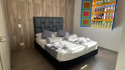 a bedroom with a bed with white sheets and purple pillows at Apto Moderno, Ubicacion Perfecta, a media calle del Malecon y Embalse, a 8 min de la Piedra del Peñol in Guatapé