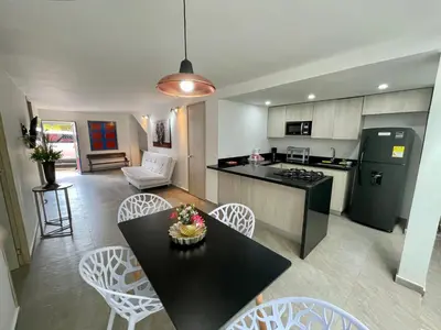 a kitchen and living room with a table and chairs at Apto Moderno, Ubicacion Perfecta, a media calle del Malecon y Embalse, a 8 min de la Piedra del Peñol in Guatapé