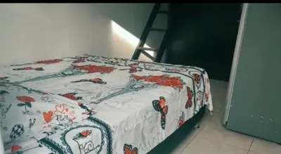 a bed with a flowered blanket on it with a ladder at Apartamento vacacional en Medellín central privado y tranquilo in Medellín