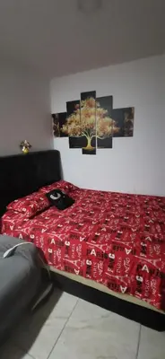 a bed with a red comforter in a room at Apartamento vacacional en Medellín central privado y tranquilo in Medellín