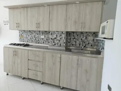a kitchen with wooden cabinets and a sink and a microwave at Apartamento Centro Guatapé, parque y embalse in Guatapé
