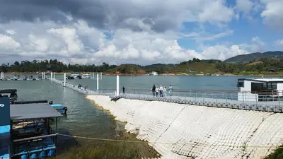 people walking on a pier next to a body of water at Apartamento Centro Guatapé, parque y embalse in Guatapé