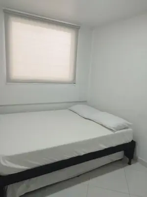 a bed in a white room with a window at Apartamento Centro Guatapé, parque y embalse in Guatapé