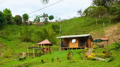 a small house on a hill with a green slope at Cabaña Glamping Los Canarios San Rafael, Antioquia in San Rafael