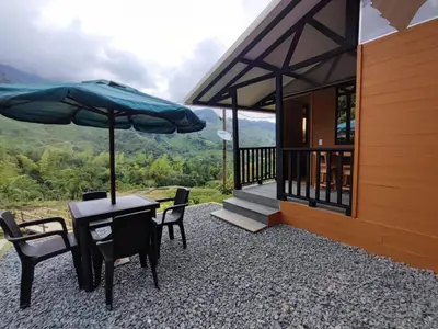 a patio with a table and chairs and an umbrella at Cabaña Glamping Los Canarios San Rafael, Antioquia in San Rafael