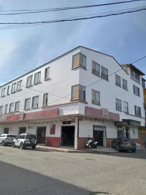 a white building with cars parked in front of it at HOTEL DORADO PUERTO BERRIO in Puerto Berrío