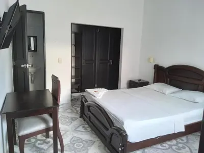 a bedroom with a bed and a table and a desk at HOTEL DORADO PUERTO BERRIO in Puerto Berrío