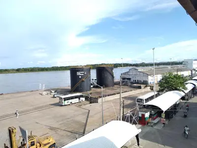 a dock with buses and trucks on the water at HOTEL DORADO PUERTO BERRIO in Puerto Berrío